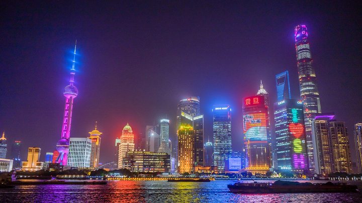 The Lujiazui skyline in Shanghai lit up at night, seen across the Huangpu River.